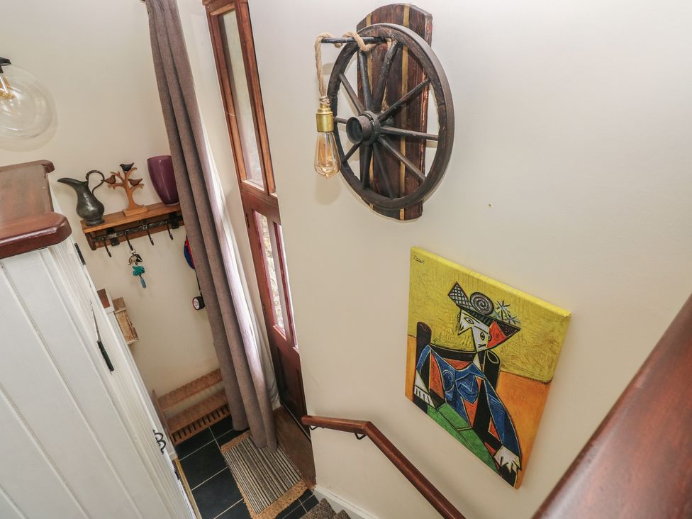A hallway with a light fixture and wall art at Coach House Haverfordwest near Broad Haven