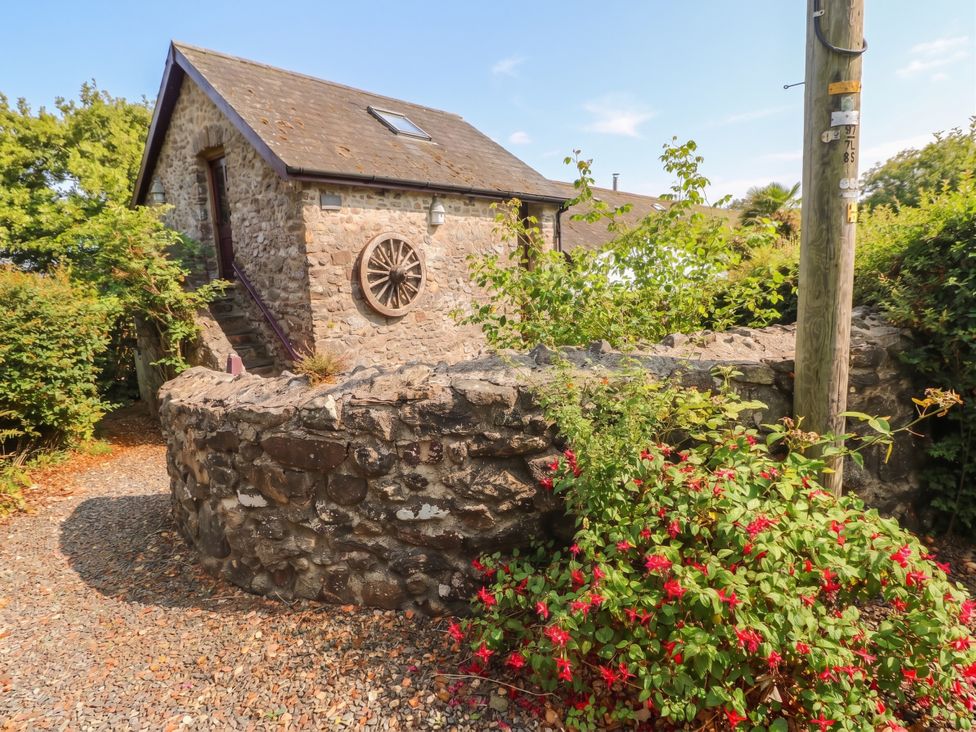 A stone building with a flower bush and steps at Coach House Haverfordwest near Broad Haven