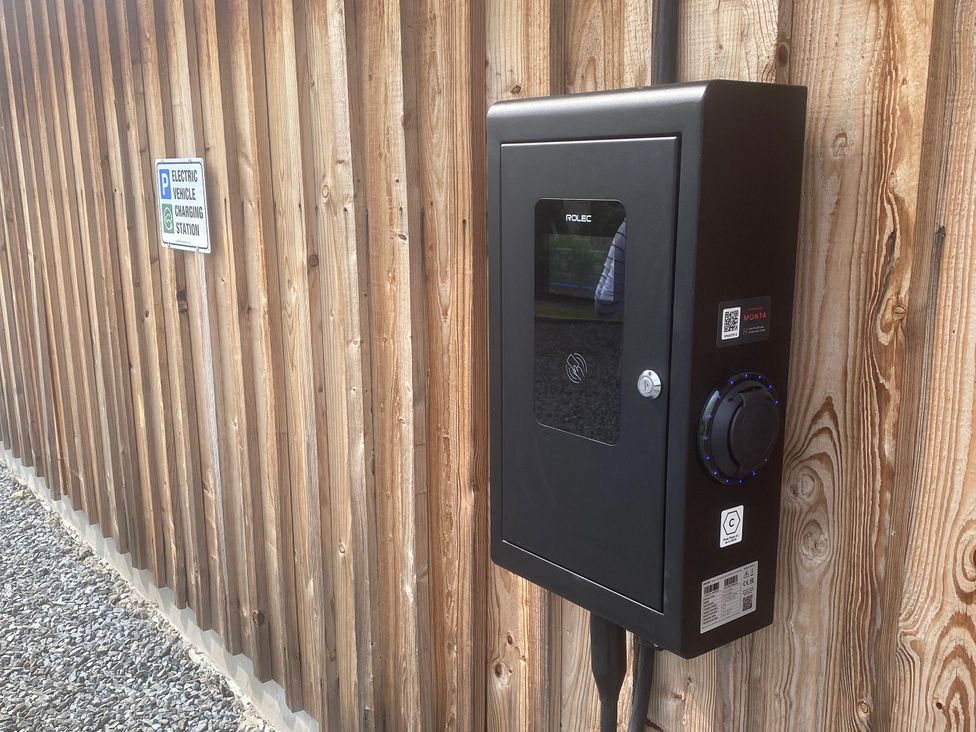 An electric vehicle charging station mounted on a wooden wall at Kalipé in Kenmore