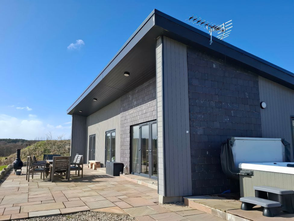 An outdoor area with a hot tub and seating at Red Squirrel in Dornoch