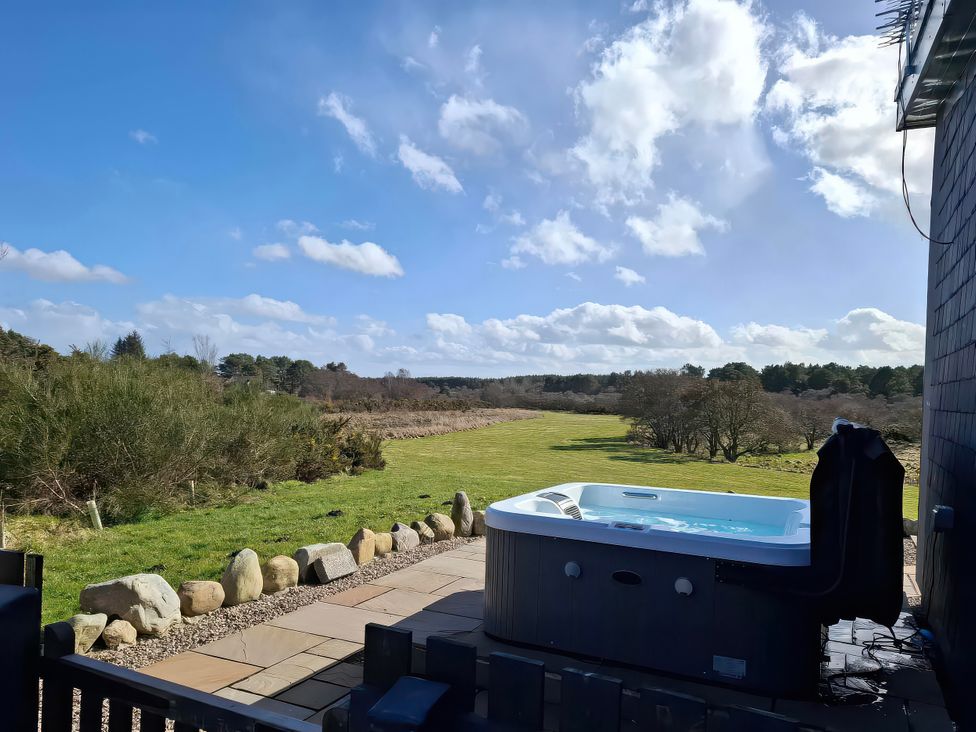 An outdoor area with a hot tub and grass at Red Squirrel in Dornoch