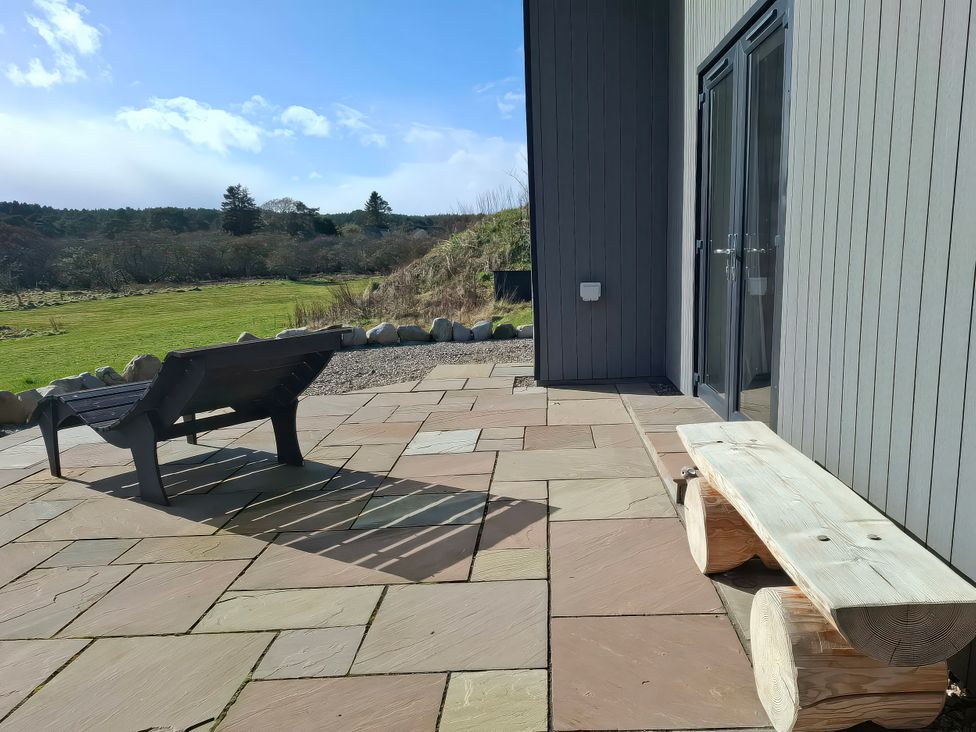 An outdoor patio with a lounge chair and wooden bench at Red Squirrel in Dornoch