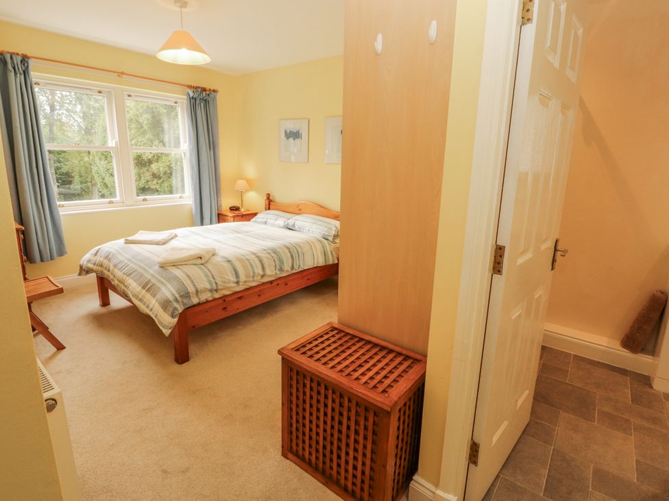 A bedroom with a bed, bedside lamp and wardrobe at Flat 17 in Keswick