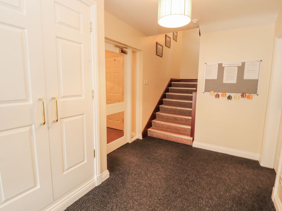A hallway with a staircase and a wardrobe at Flat 17 in Keswick