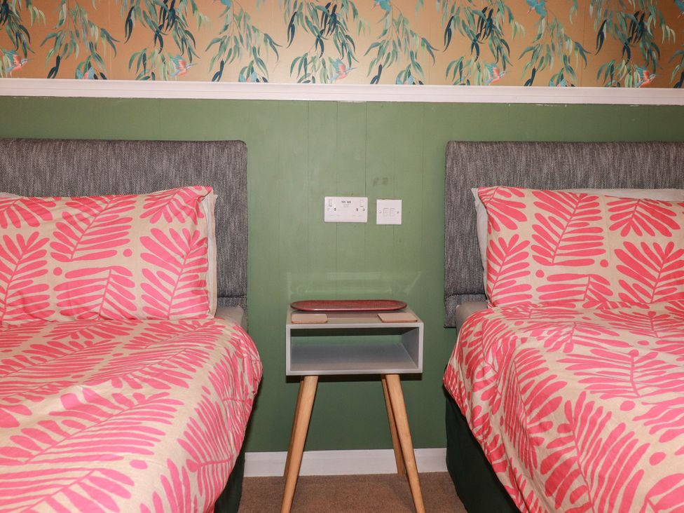 A bedroom with two beds and a nightstand at 64 St Columb Nr Newquay