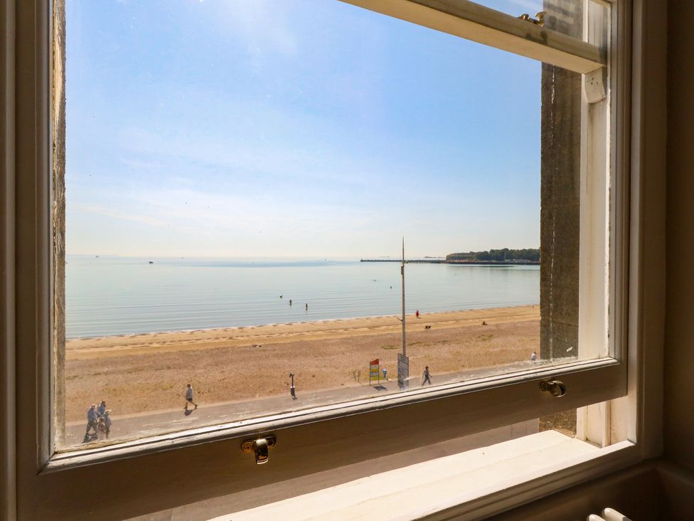 A view of the sea and beach through a window at 123 On The Sea – Victoria’s Place Weymouth