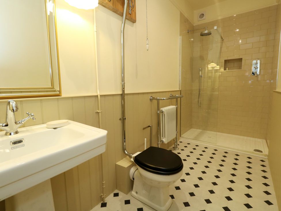 A bathroom with a sink, toilet, shower, and radiator at 123 On The Sea – Victoria’s Place Weymouth