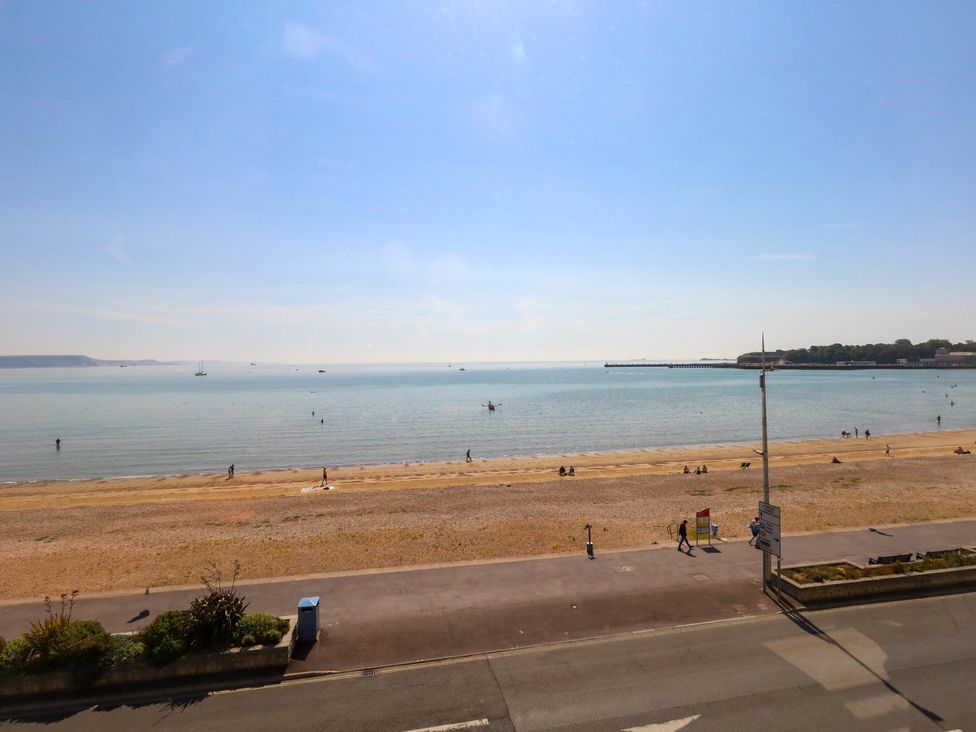 A beach with people walking and a pier at 123 On The Sea – Victoria’s Place in Weymouth