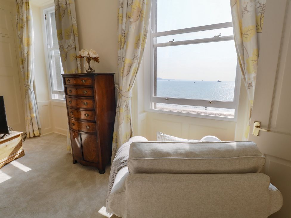 A living room with a chest of drawers and armchair at 123 On The Sea – Victoria’s Place Weymouth