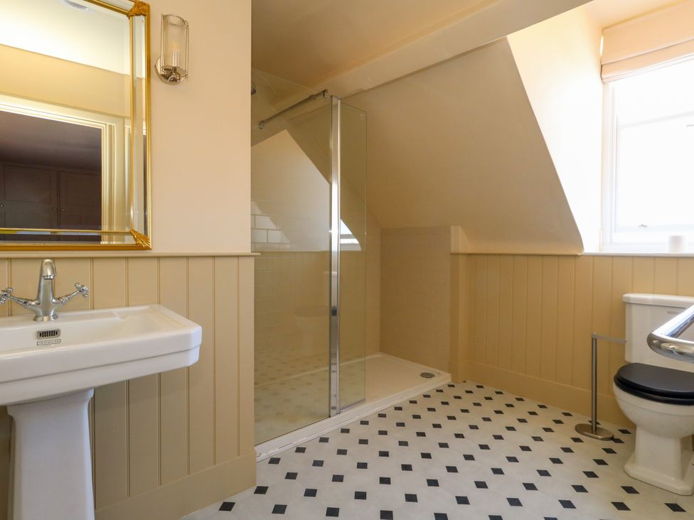 A bathroom with a sink, shower, mirror, and toilet at 123 On The Sea – The Eaves in Weymouth
