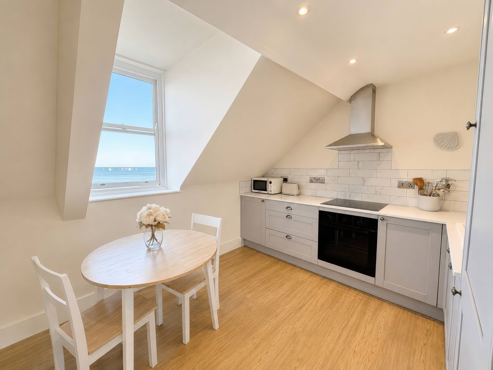 A kitchen with a table and chairs at 123 On The Sea – The Eaves, Weymouth