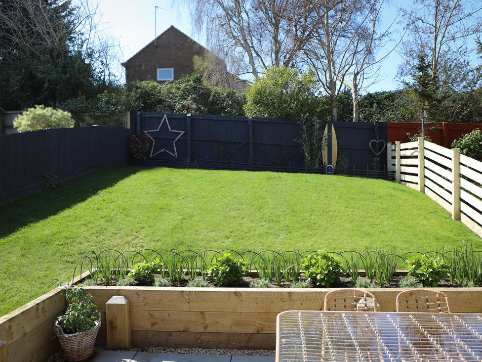A garden with grass and a wooden planter at The Nightingale in Weymouth