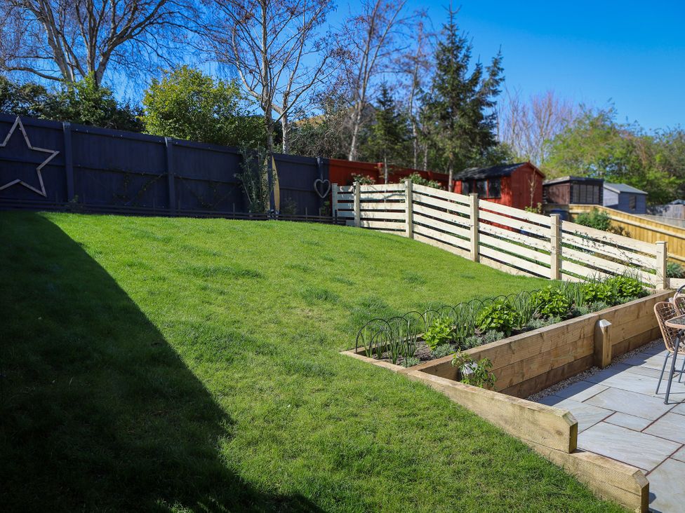A garden with grass and a flower bed at The Nightingale in Weymouth