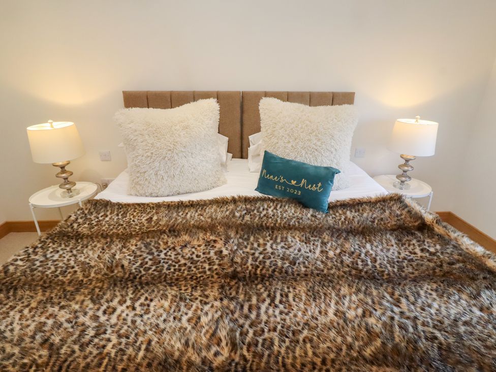 A bedroom with a bed, pillows, bedside table, and lamp at Nene's Nest in Alnwick