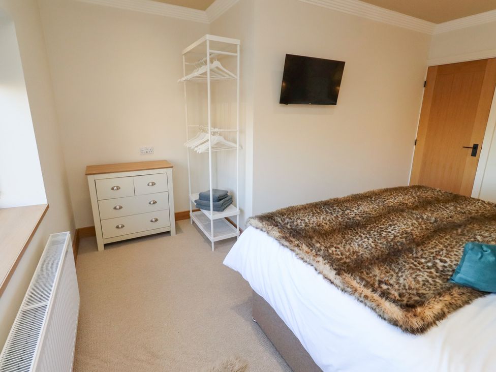A bedroom with a bed, dresser, and clothes hanger at Nene's Nest in Alnwick