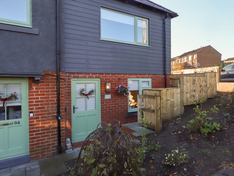 An exterior view of a house with green doors and a wooden fence at Nene's Nest Alnwick