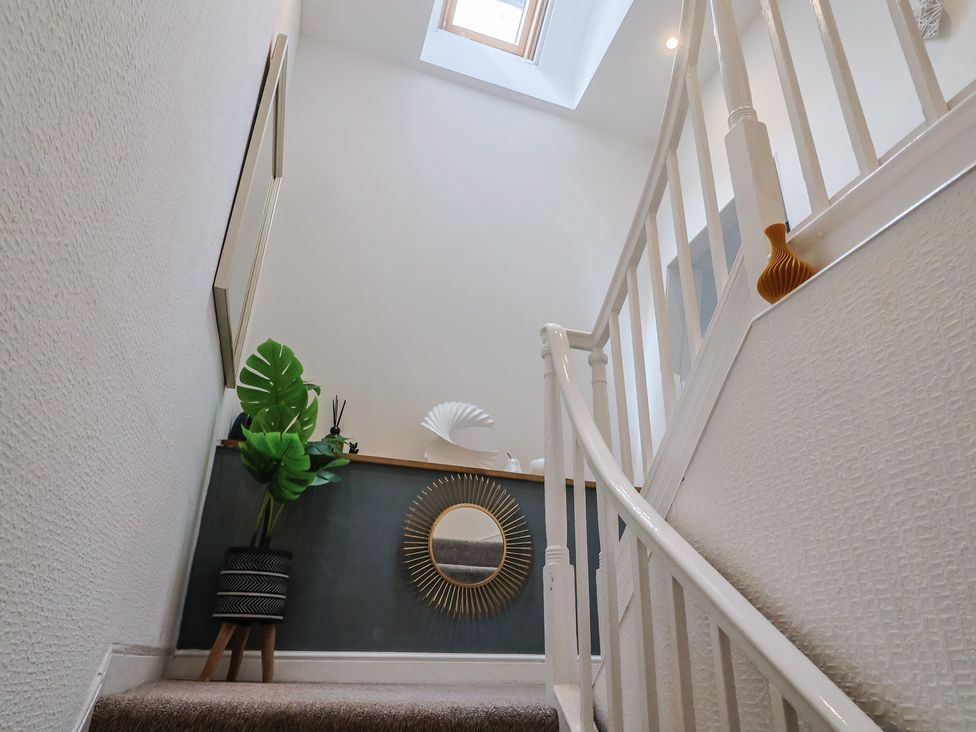 A staircase with a plant and mirror at Jasper in Lyme Regis