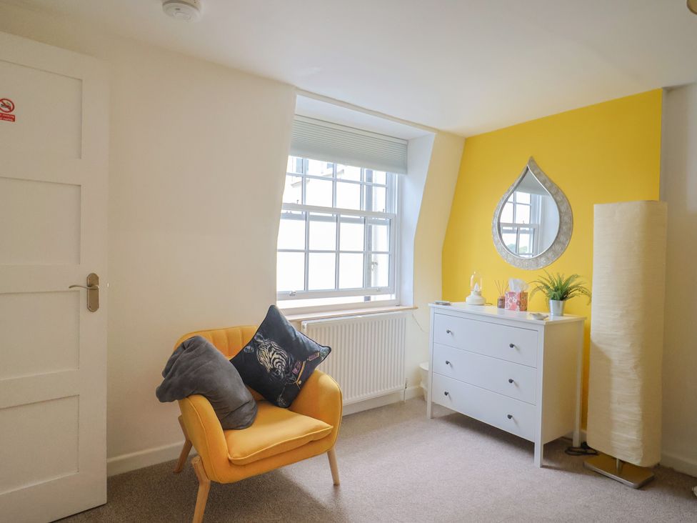 A bedroom with an armchair and dresser at Jasper in Lyme Regis