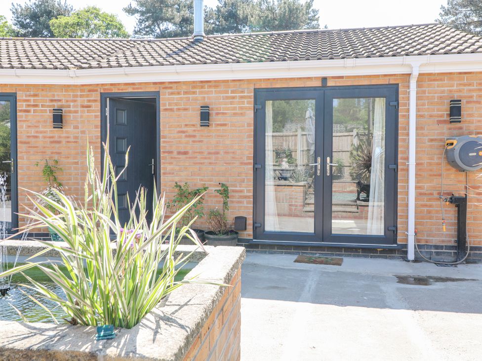 A brick house exterior with black doors and a rectangular planter with tall grass at La Casa Lipa in Nottingham