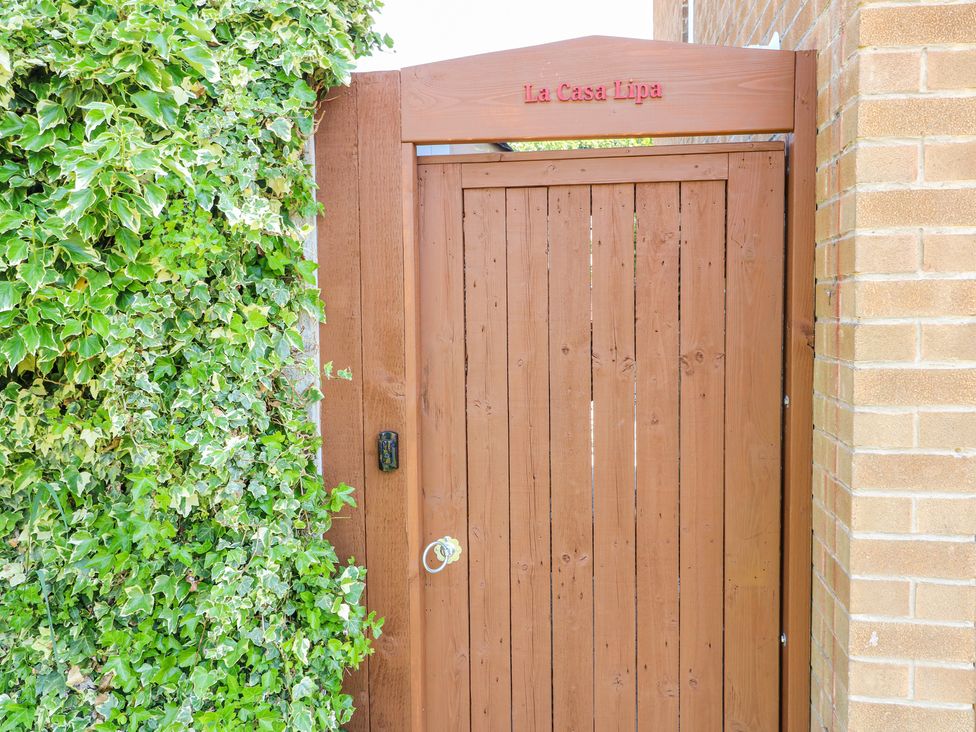 A wooden gate with the name La Casa Lipa on top surrounded by green ivy and a brick wall at La Casa Lipa in Nottingham