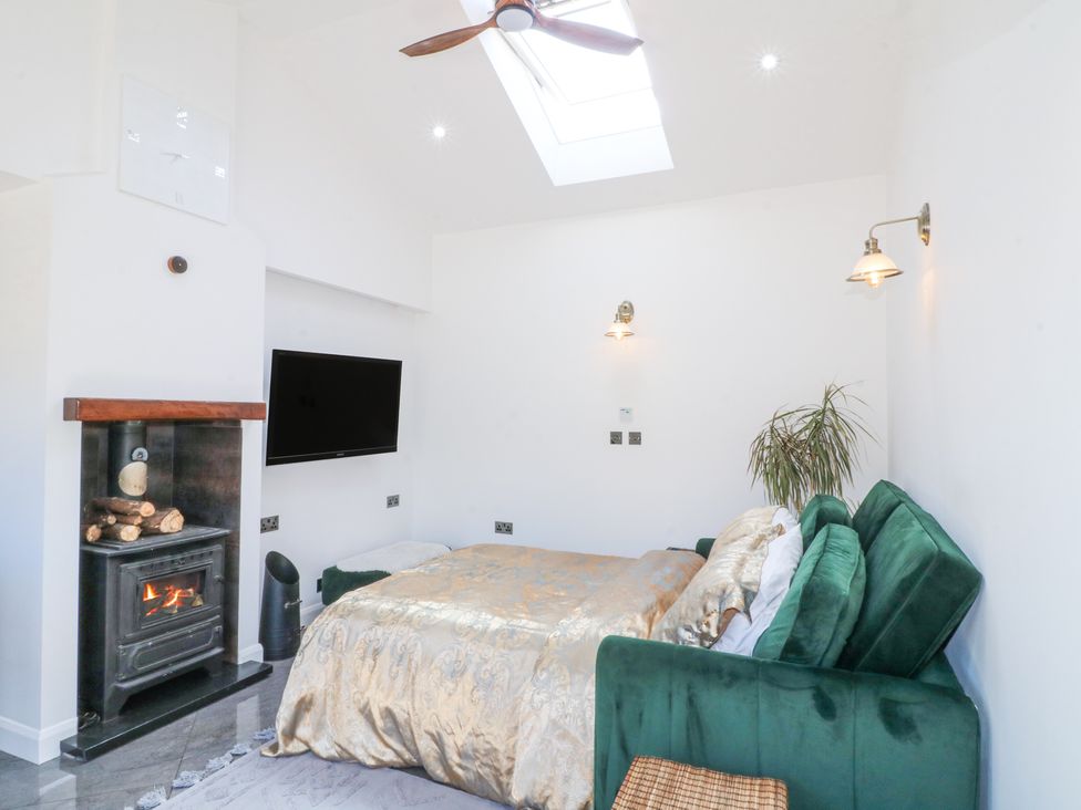 A bedroom with a green sofa bed next to a fireplace and a wall-mounted TV at La Casa Lipa in Nottingham