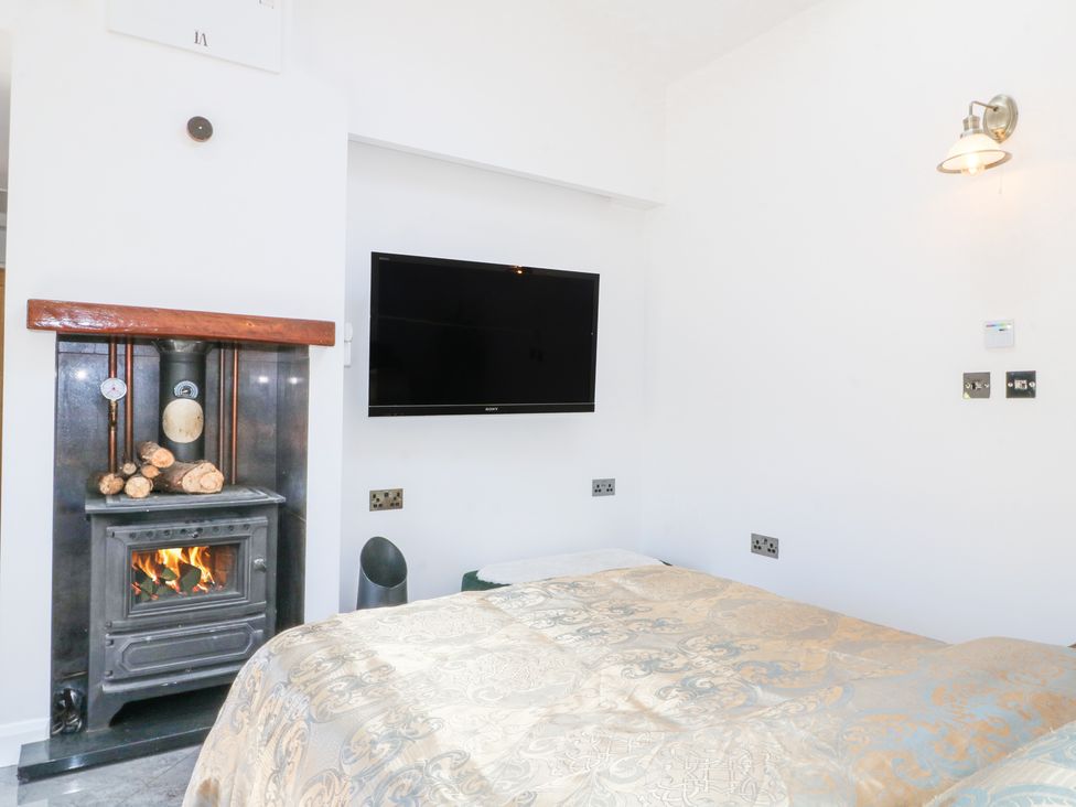 A bedroom with a bed a wood burning stove and a wall mounted television at La Casa Lipa in Nottingham