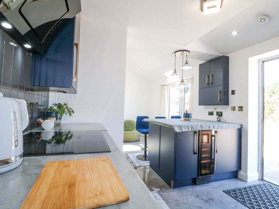 A kitchen with an island, bar stools, cutting board on countertop, and a kettle at La Casa Lipa in Nottingham