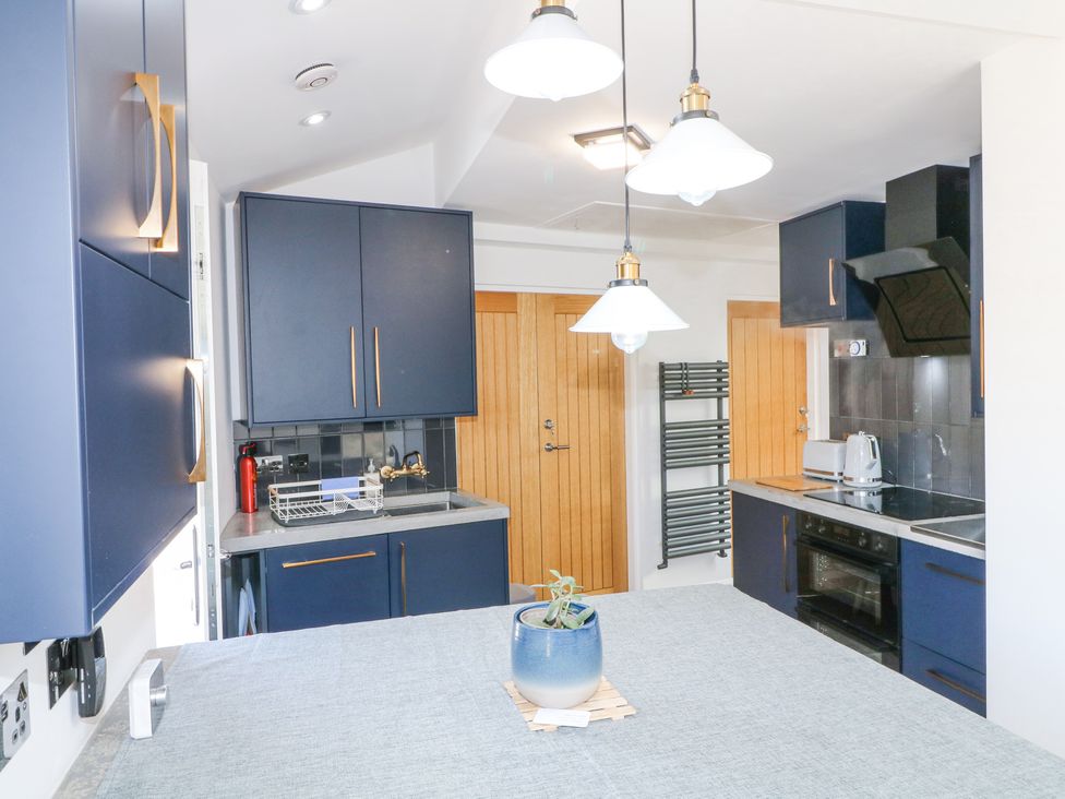 A kitchen with blue cabinets a sink oven stovetop and pendant lights at La Casa Lipa in Nottingham