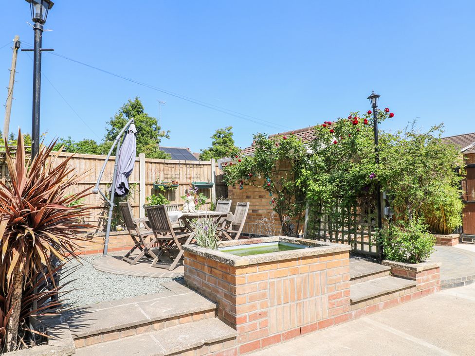 An outdoor patio with wooden chairs and table a small water fountain and plants at La Casa Lipa in Nottingham