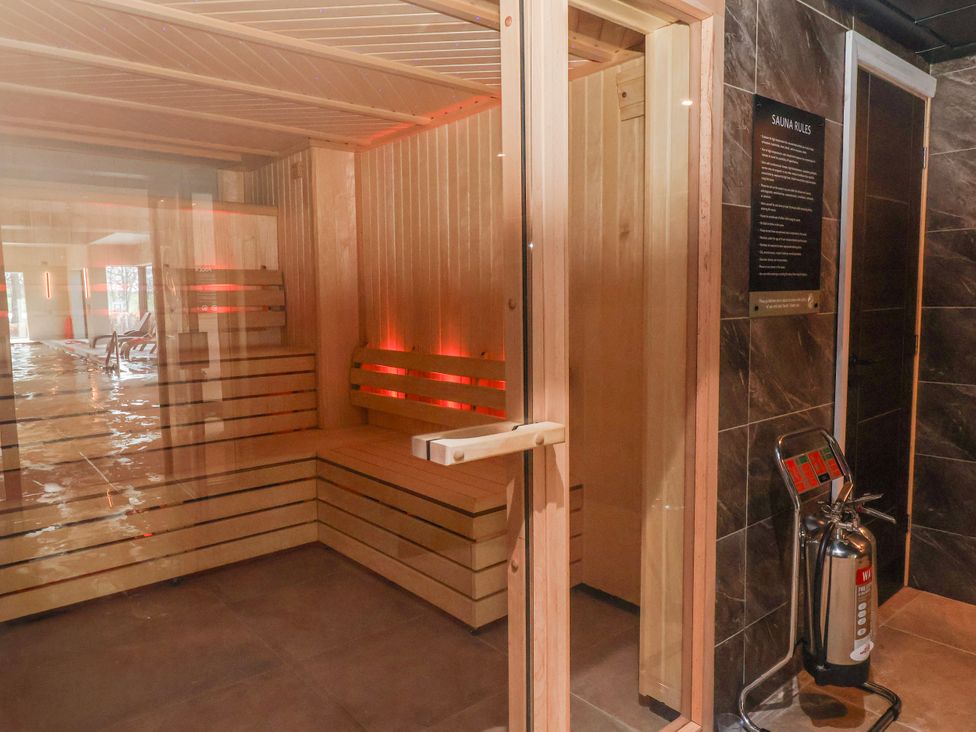 A sauna with wooden benches and a fire extinguisher at Woodlands Retreat Llanfwrog near Ruthin