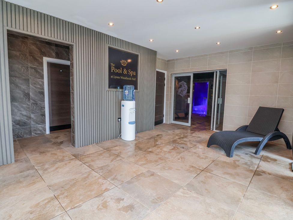A spa area with a lounge chair and a water cooler at Woodlands Retreat Llanfwrog near Ruthin