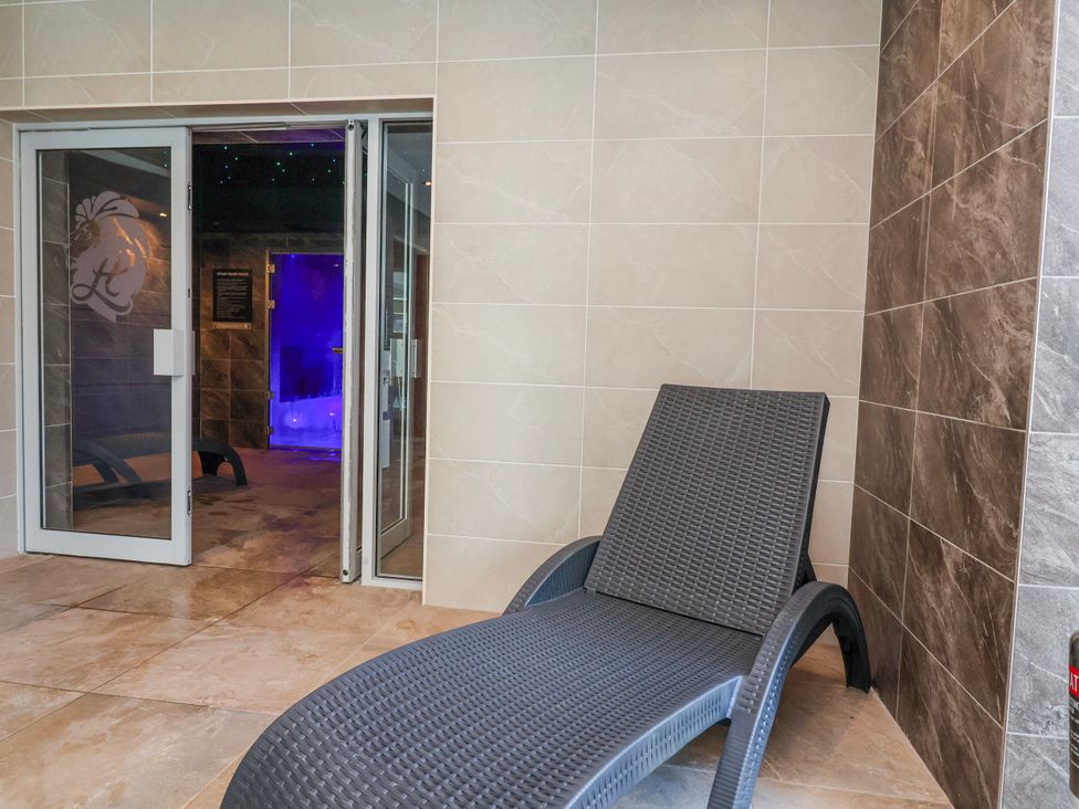 A sun lounger by a door leading to a steam room at Woodlands Retreat in Llanfwrog near Ruthin