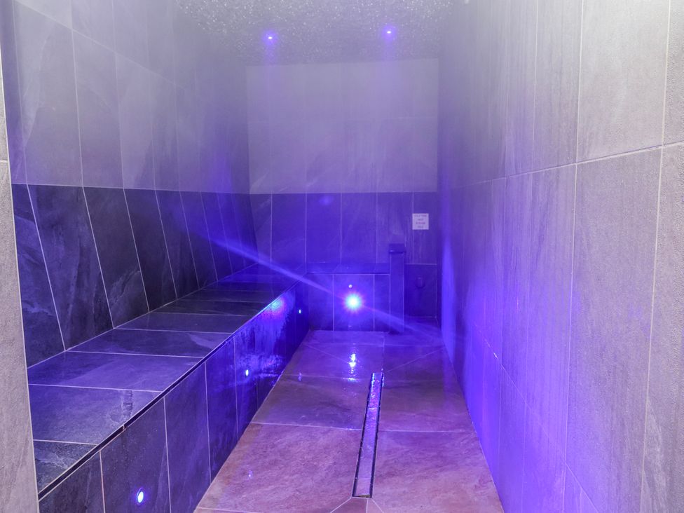 A steam room with benches and tiled walls at Woodlands Retreat in Llanfwrog near Ruthin