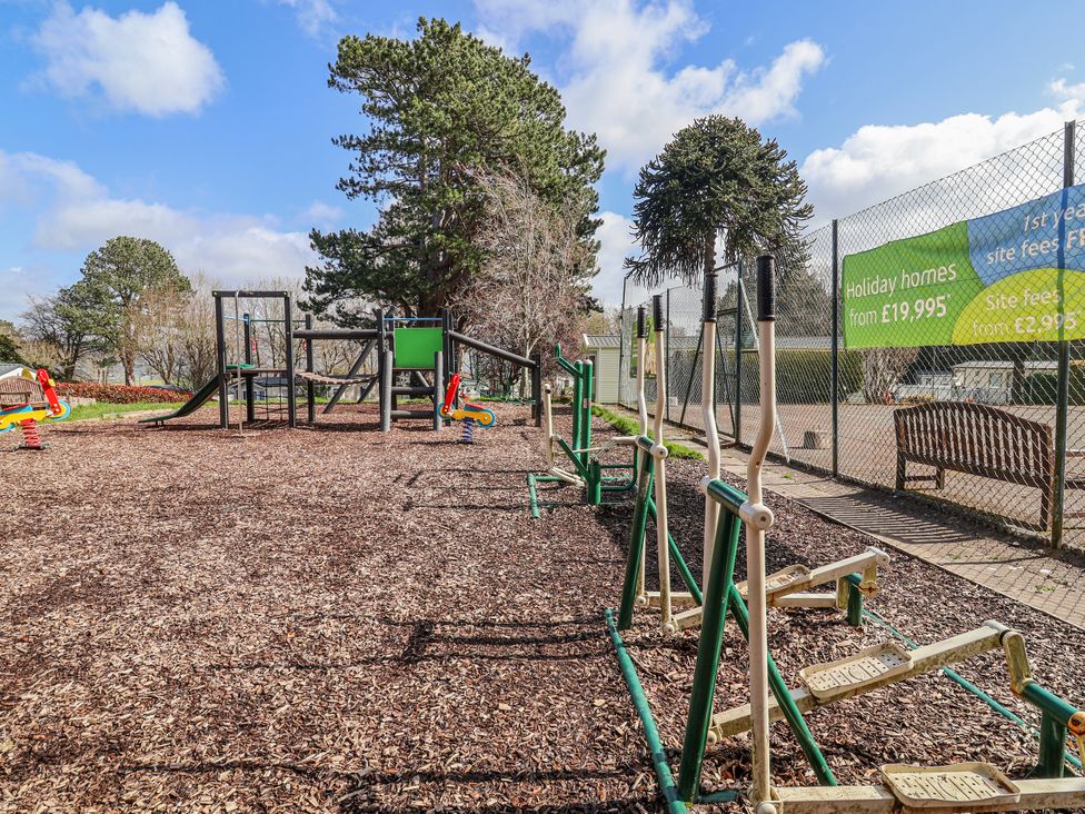A playground with exercise equipment and a bench at Woodlands Retreat in Llanfwrog near Ruthin