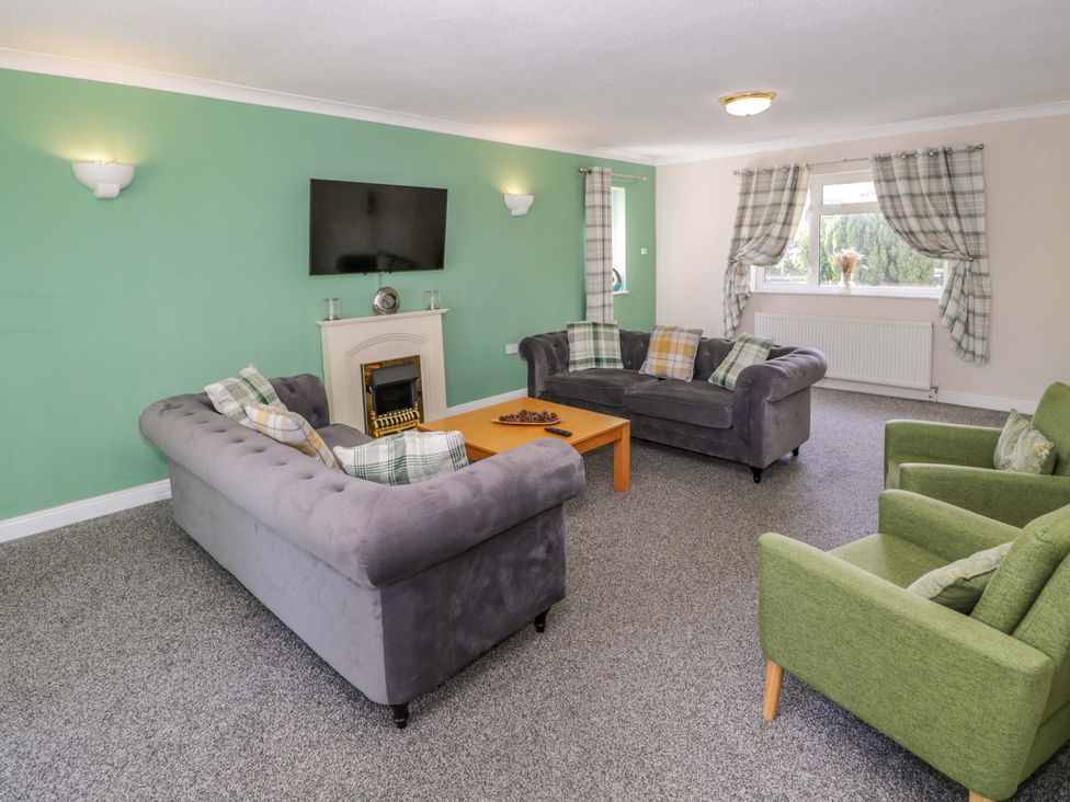 A living room with a fireplace and sofa at Woodlands Retreat Llanfwrog near Ruthin