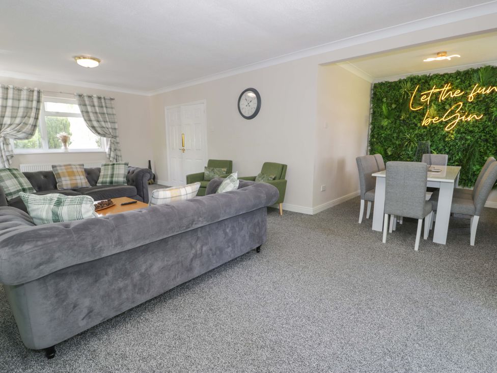 A living room with a sofa and dining area at Woodlands Retreat in Llanfwrog near Ruthin