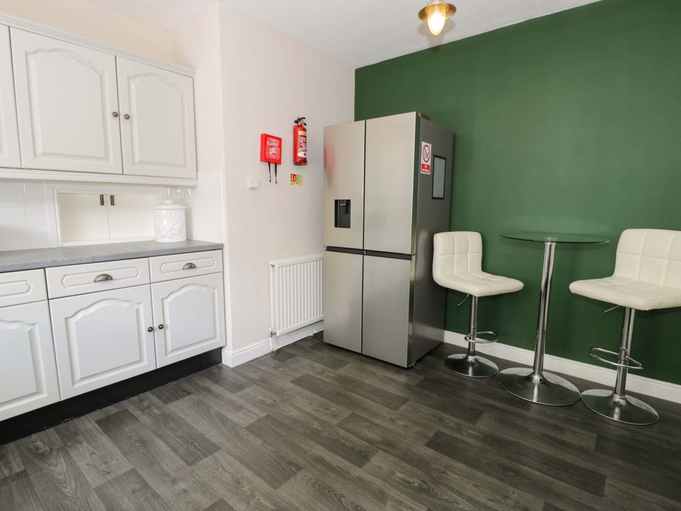 A kitchen with refrigerator and bar stools at Woodlands Retreat in Llanfwrog near Ruthin
