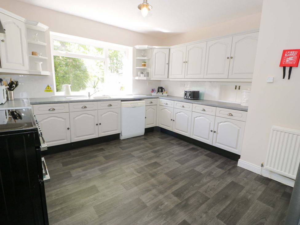 A kitchen with white cabinets and appliances at Woodlands Retreat in Llanfwrog near Ruthin