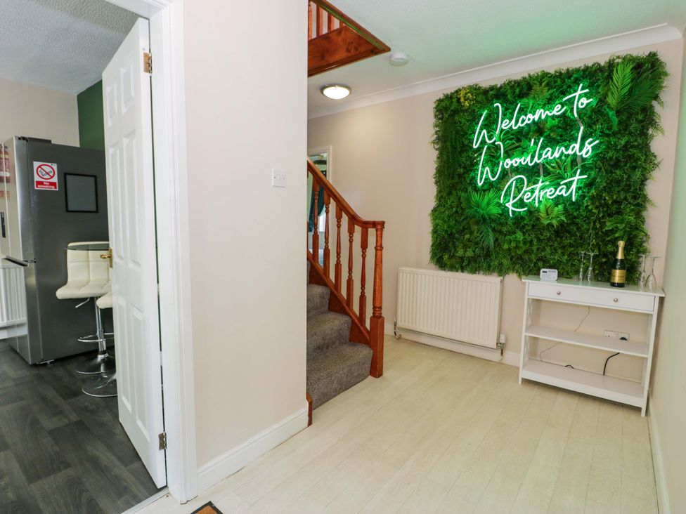 A hallway with a staircase and a neon sign at Woodlands Retreat Llanfwrog near Ruthin