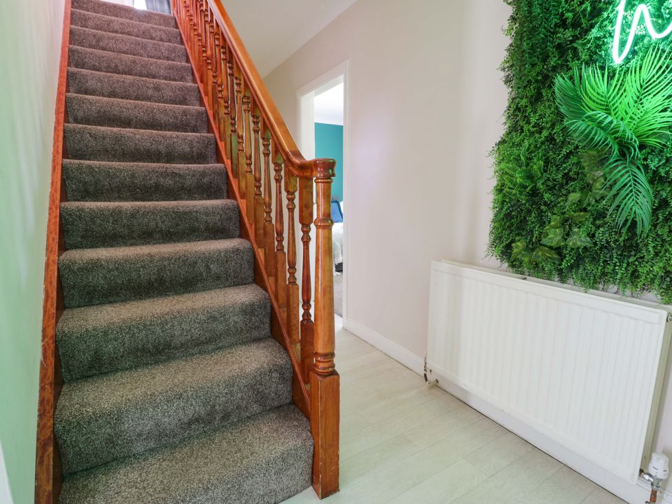 A staircase in a hallway with a radiator and green wall decor at Woodlands Retreat Llanfwrog near Ruthin