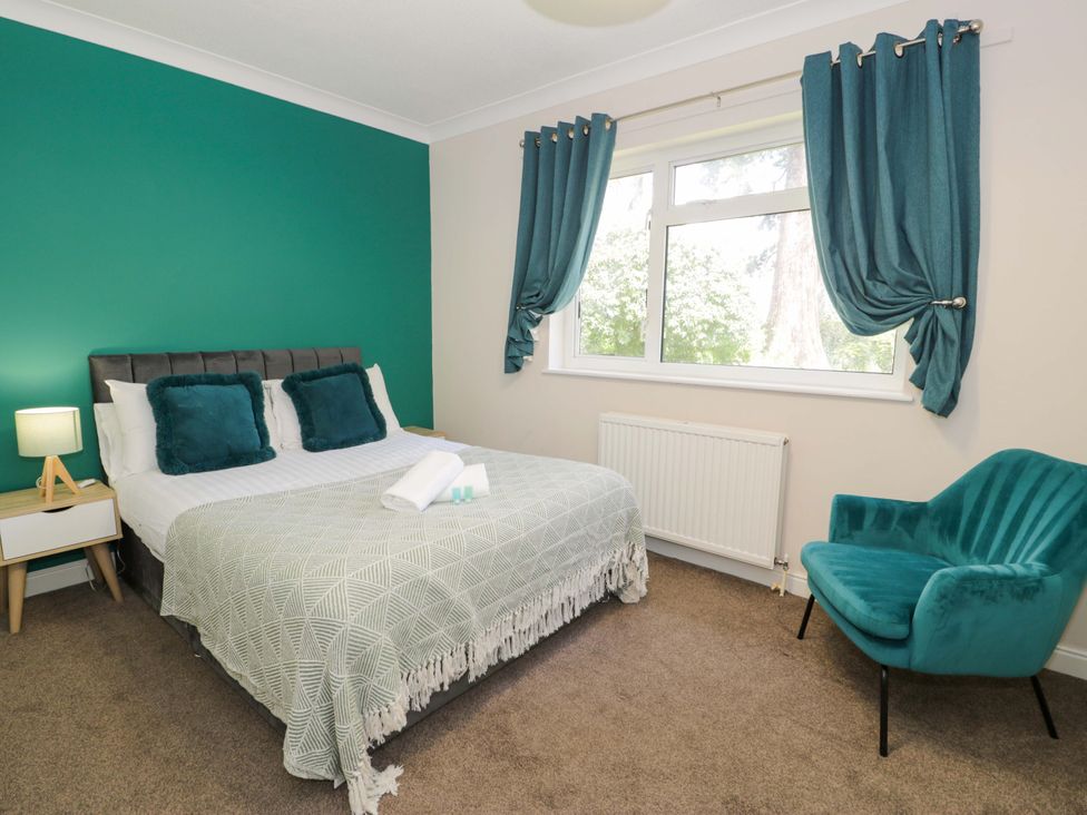 A bedroom with a bed and chair at Woodlands Retreat in Llanfwrog near Ruthin