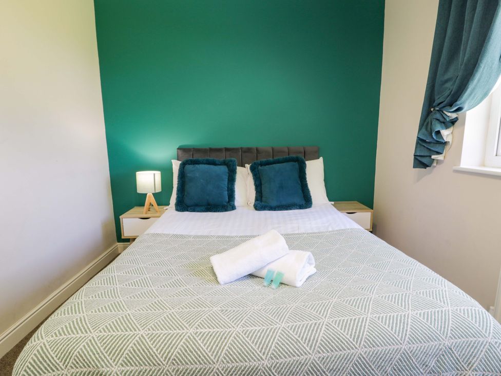 A bedroom with a bed, bedside table and towels at Woodlands Retreat in Llanfwrog near Ruthin