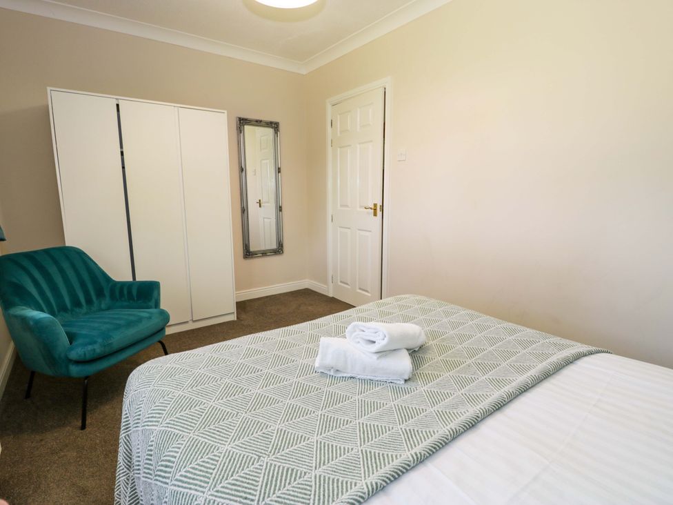 A bedroom with a bed and wardrobe at Woodlands Retreat in Llanfwrog near Ruthin