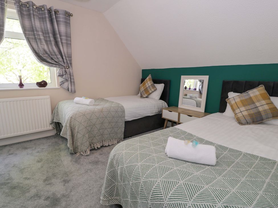 A bedroom with two beds and a nightstand at Woodlands Retreat near Llanfwrog