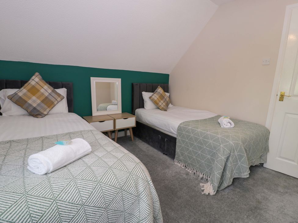 A bedroom with two beds and a mirror at Woodlands Retreat in Llanfwrog near Ruthin
