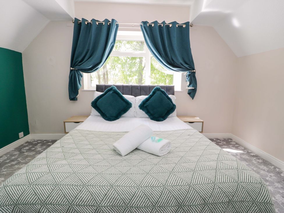 A bedroom with a bed and cushions at Woodlands Retreat in Llanfwrog near Ruthin