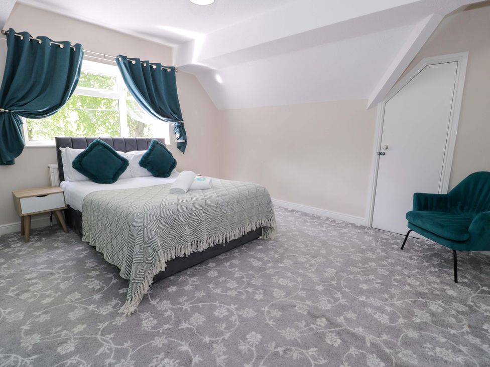 A bedroom with a bed and chair at Woodlands Retreat Llanfwrog near Ruthin