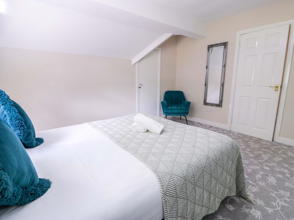 A bedroom with a bed and chair at Woodlands Retreat in Llanfwrog near Ruthin