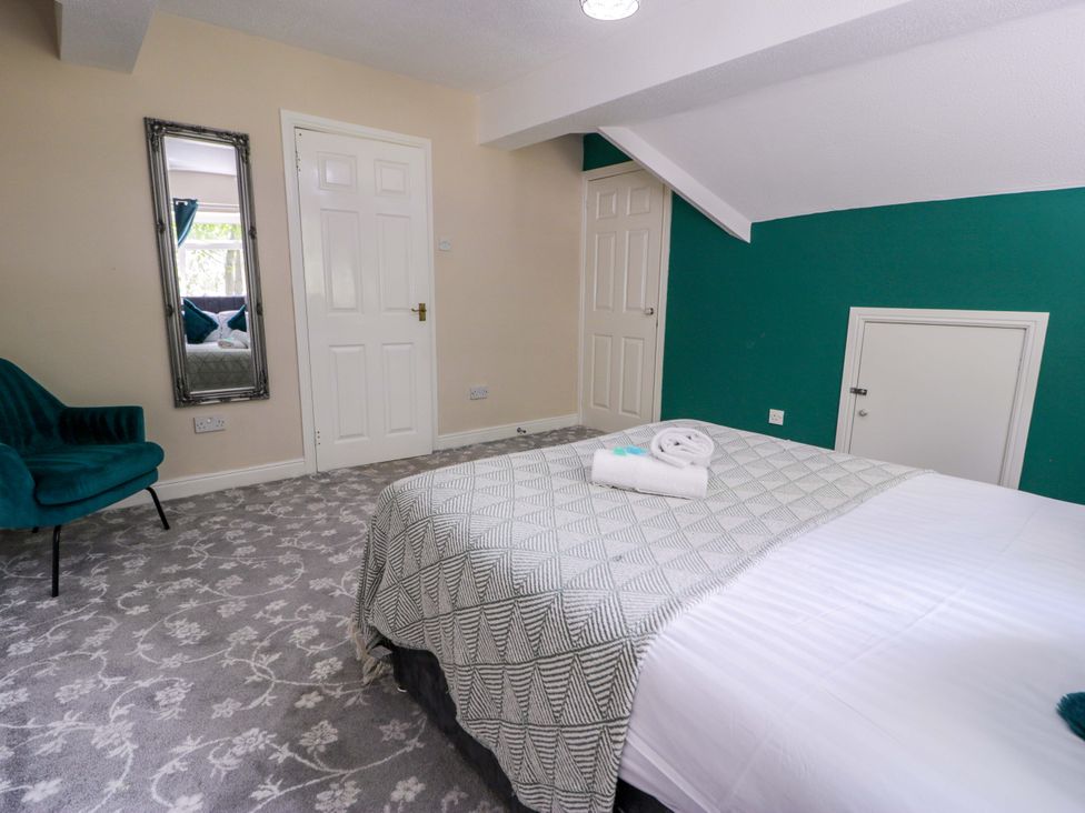 A bedroom with a bed and a mirror at Woodlands Retreat Llanfwrog near Ruthin