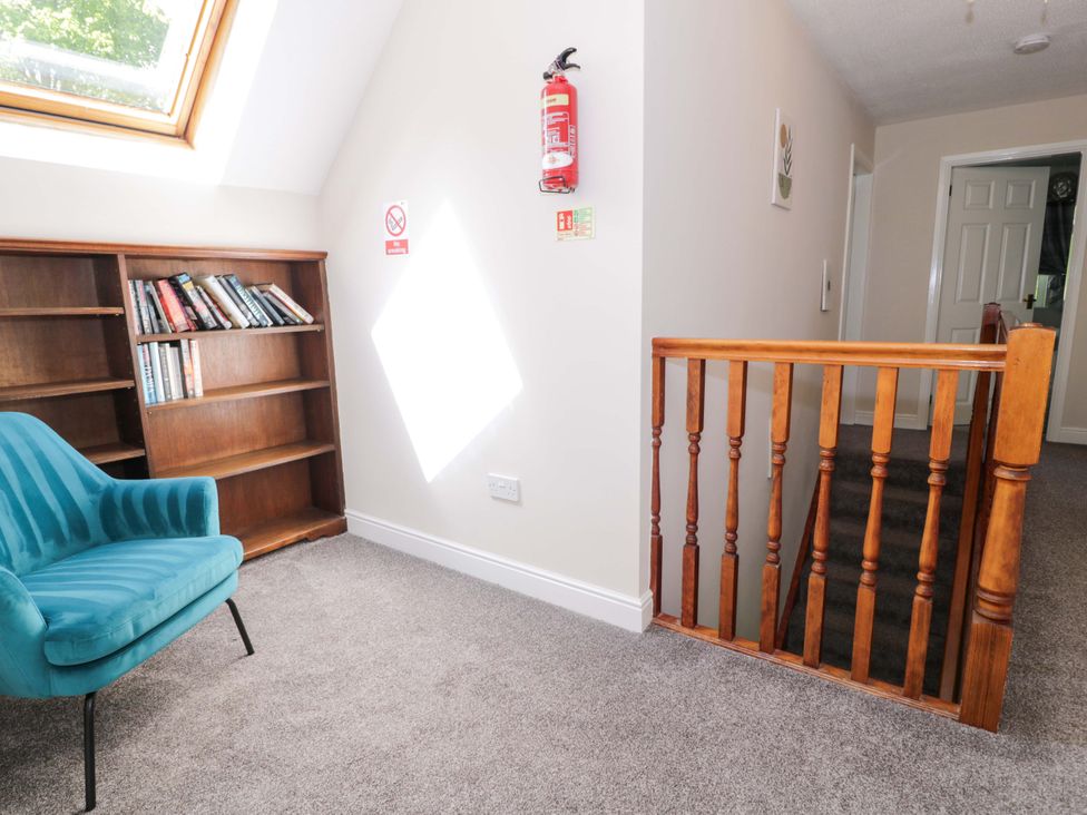 A landing with a bookshelf and a chair at Woodlands Retreat Llanfwrog near Ruthin